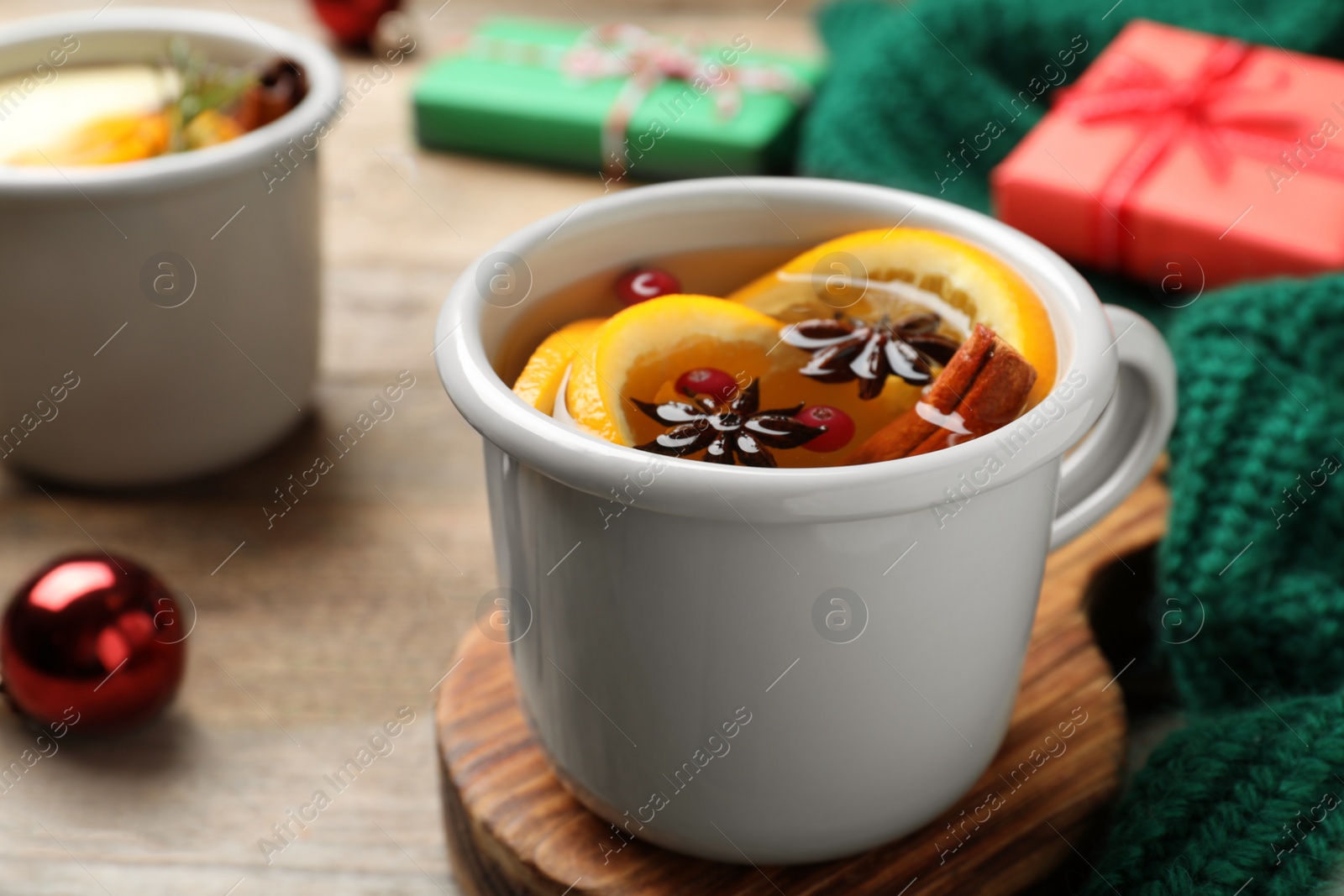 Photo of Aromatic mulled wine on wooden board, closeup