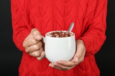 Photo of Woman holding cup of delicious hot cocoa drink with marshmallows, closeup
