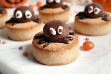 Photo of Delicious biscuit with chocolate spider on white table, closeup. Halloween celebration