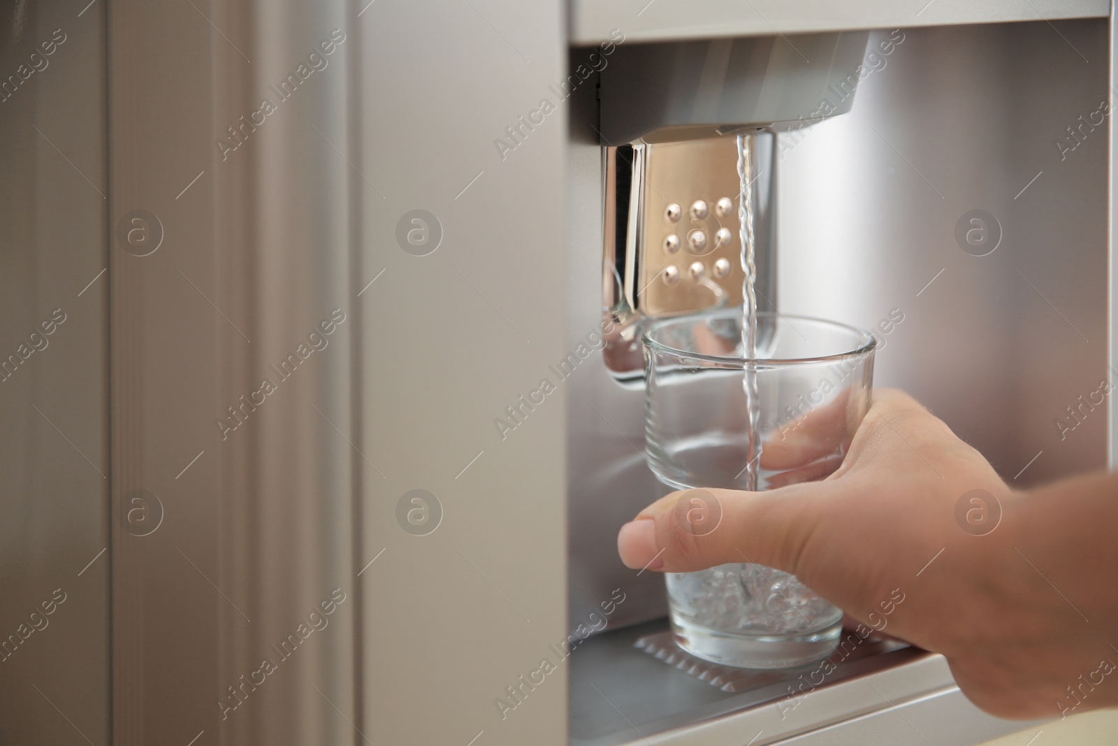 Photo of Woman filling glass with water from modern cooler, closeup