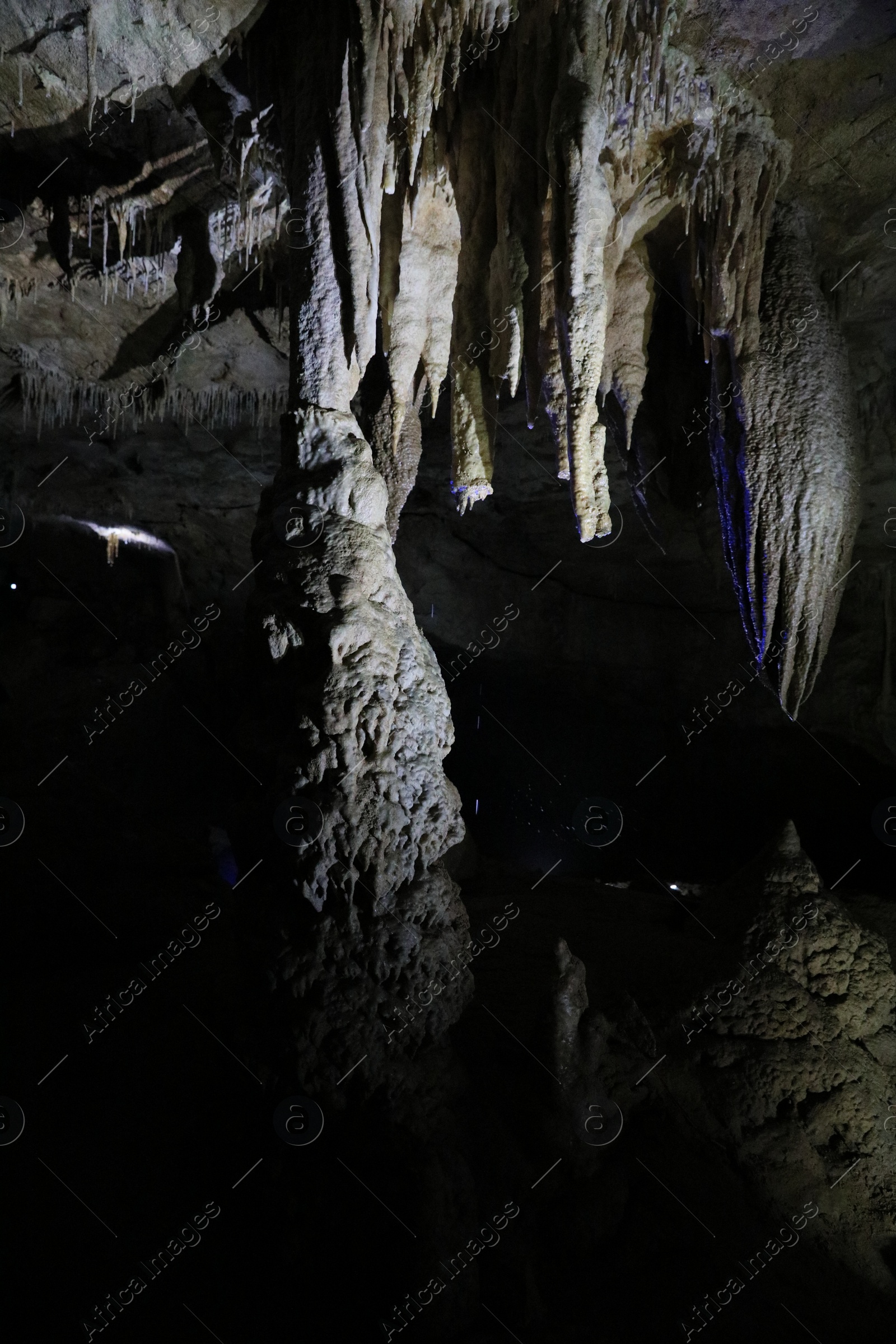 Photo of Picturesque view of many stalactite and stalagmite formations in dark cave