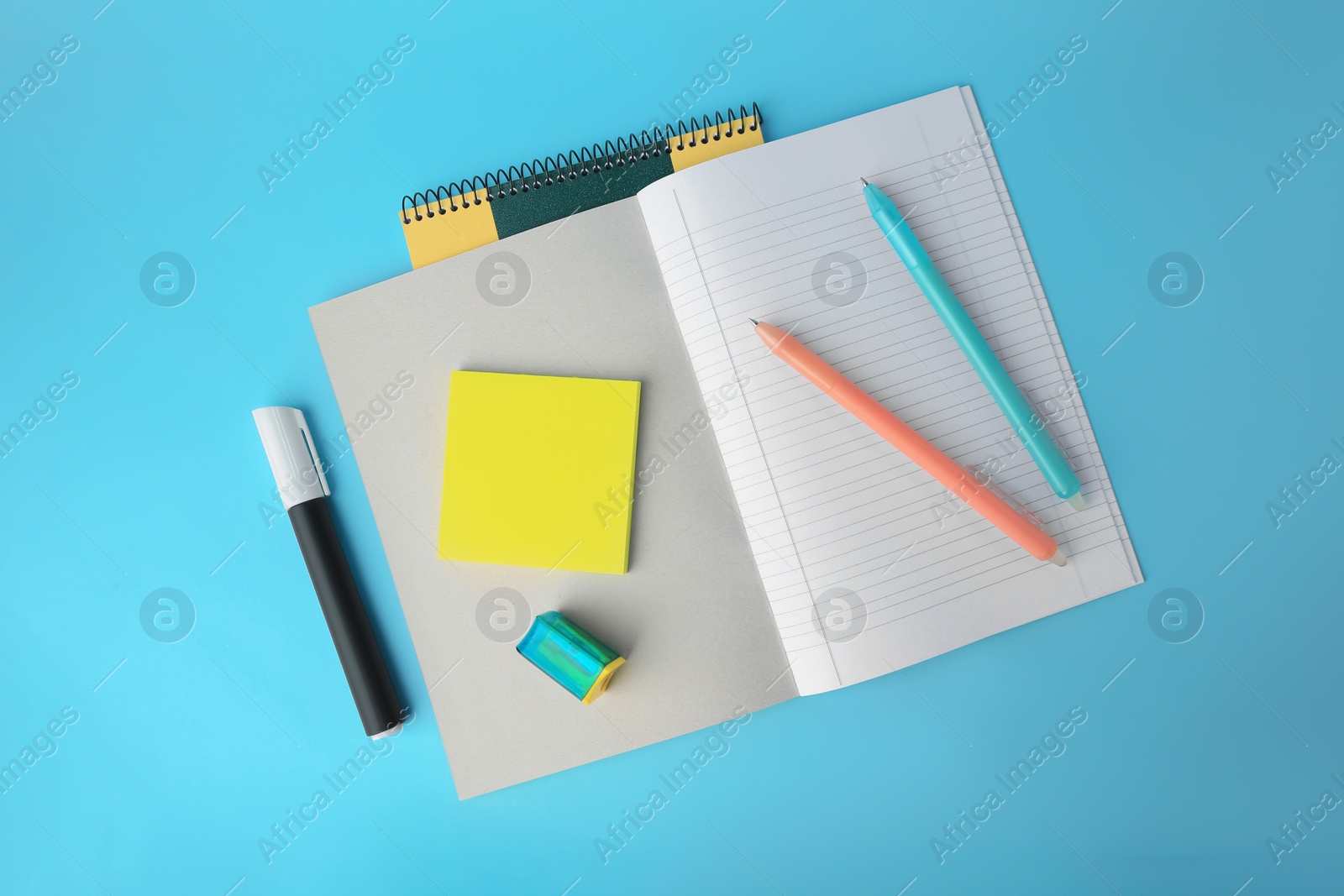 Photo of Flat lay composition with erasable pens and copybook on light blue background