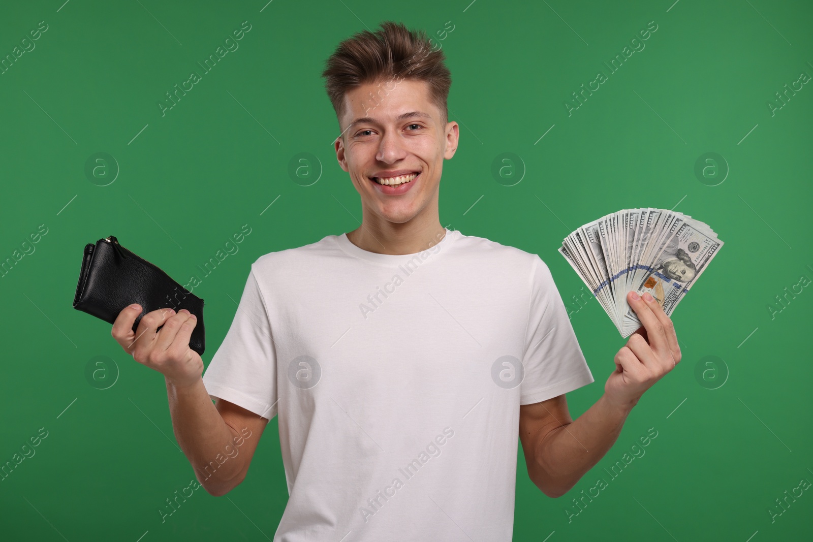 Photo of Happy man with wallet and dollar banknotes on green background