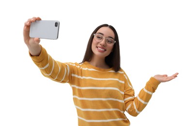 Smiling young woman taking selfie with smartphone on white background