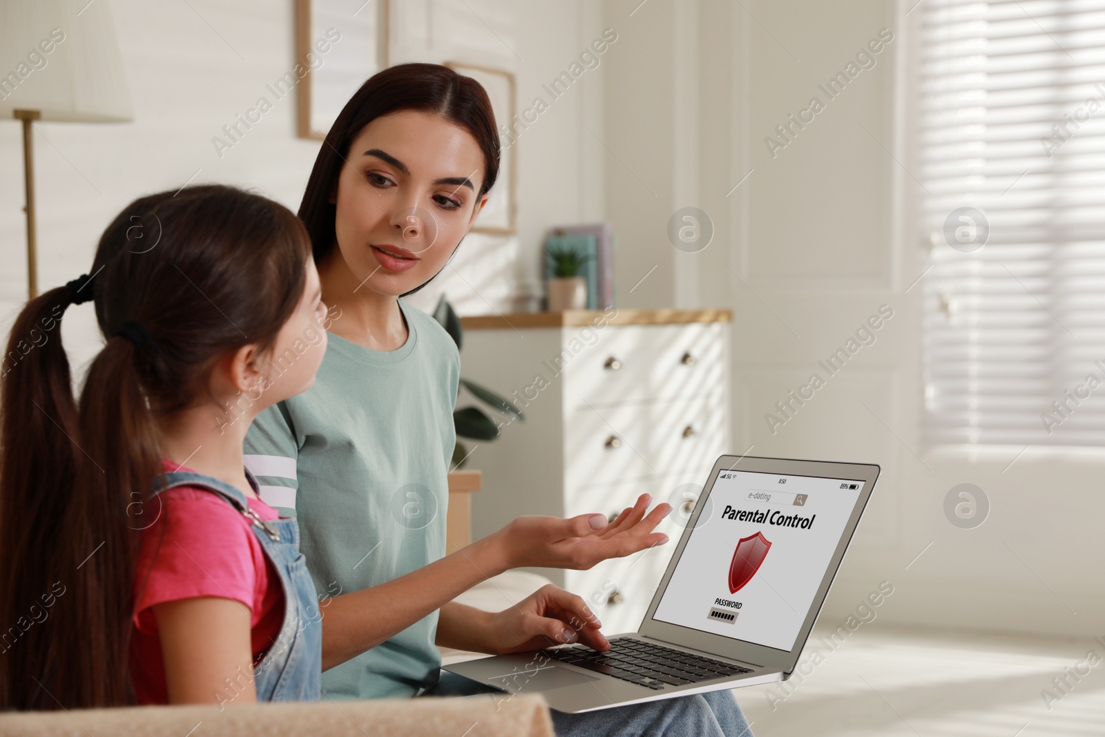 Photo of Mother installing parental control app on laptop to ensure her child's safety at home