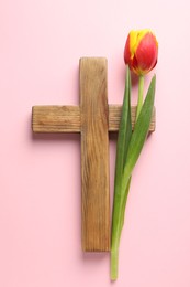 Photo of Easter - celebration of Jesus resurrection. Wooden cross and tulip on pink background, top view