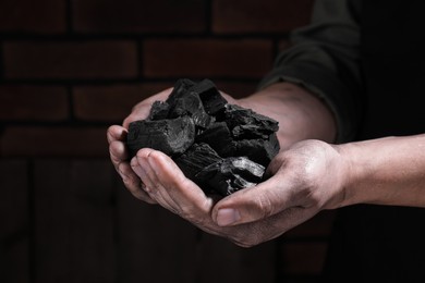 Photo of Man with handful of coal near brick wall, closeup view