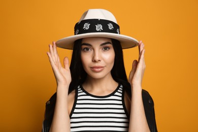 Photo of Fashionable young woman in stylish outfit with bandana on orange background