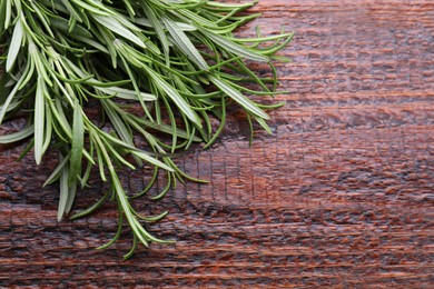 Photo of Fresh green rosemary twigs on wooden table, closeup. Space for text