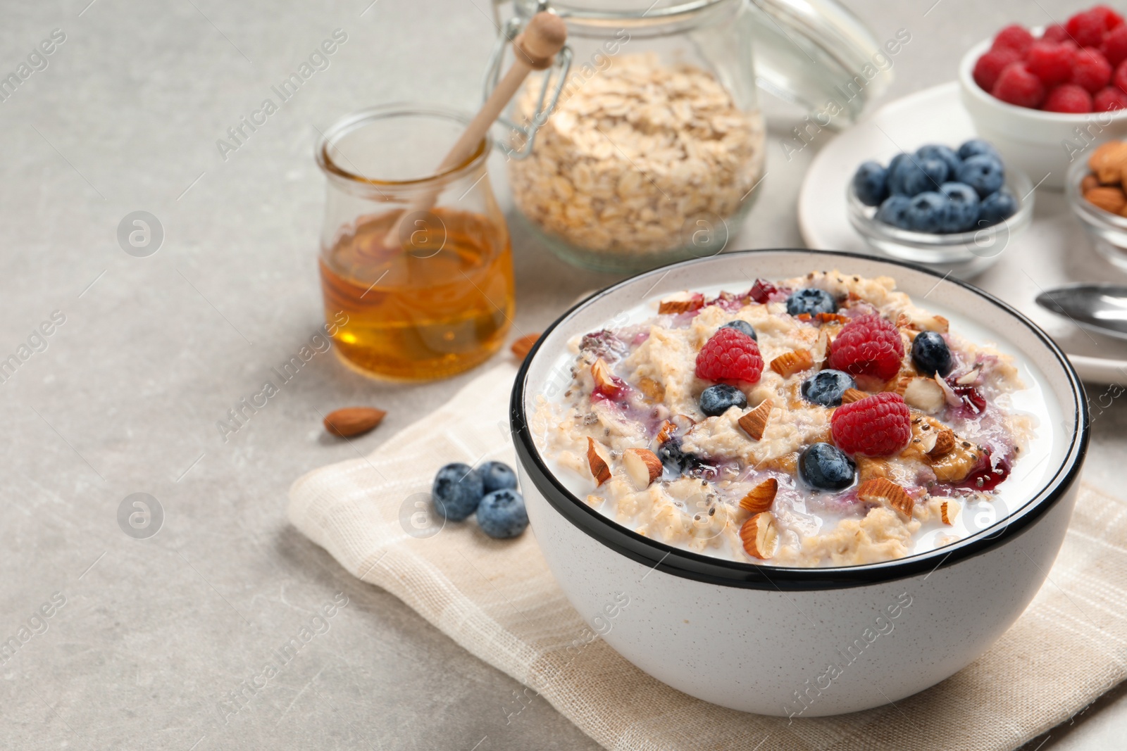 Photo of Tasty oatmeal porridge with toppings served on grey table. Space for text