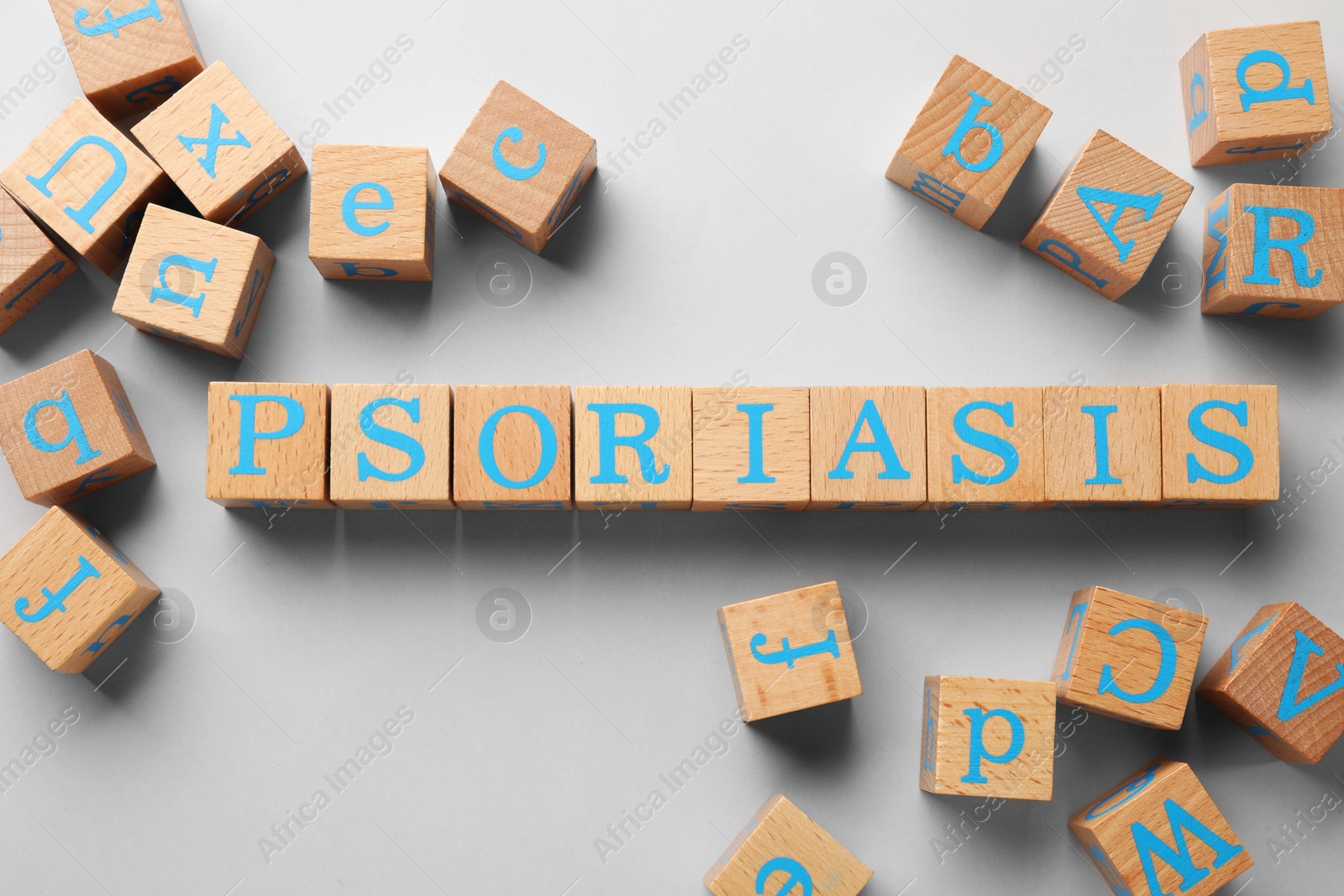 Photo of Word Psoriasis made of wooden cubes with letters on light grey background, flat lay