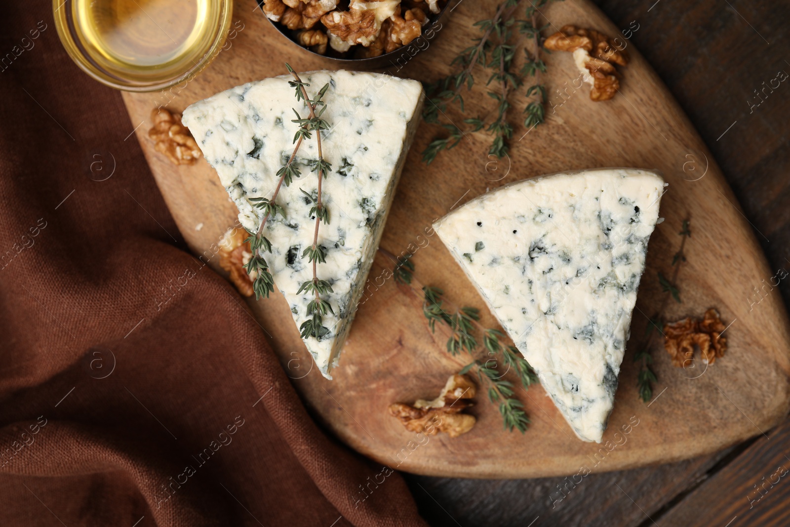 Photo of Tasty blue cheese with thyme, honey and walnuts on wooden table, top view