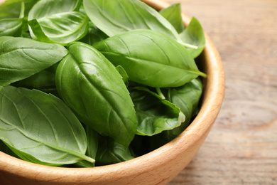 Photo of Fresh basil leaves on wooden table, closeup