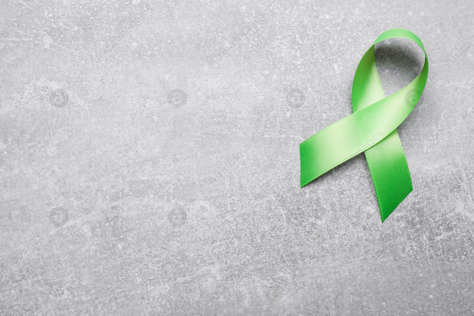 Photo of World Mental Health Day. Green ribbon on light grey background, top view with space for text