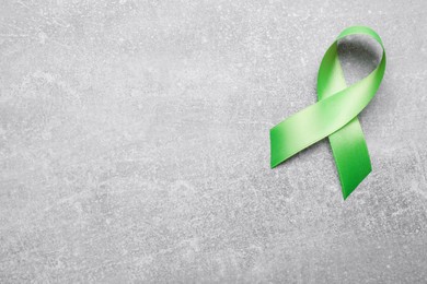 Photo of World Mental Health Day. Green ribbon on light grey background, top view with space for text