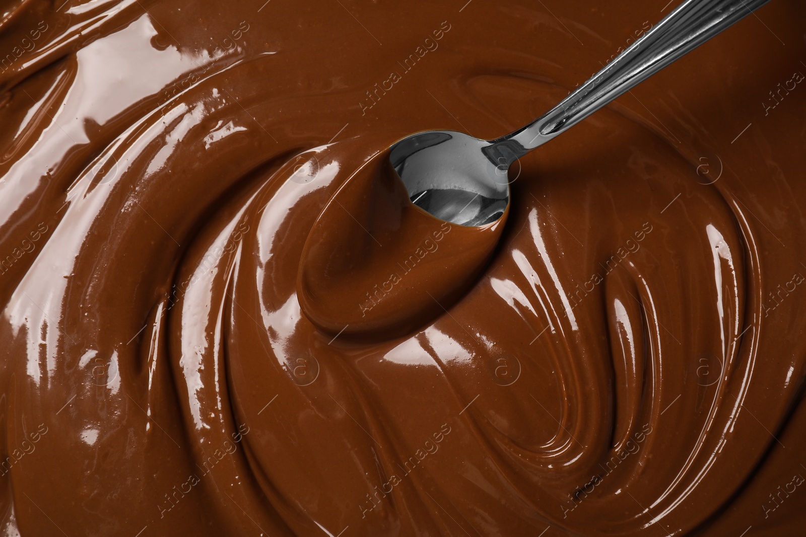 Photo of Spoon with tasty milk chocolate paste as background, top view
