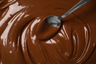 Photo of Spoon with tasty milk chocolate paste as background, top view