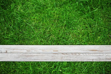 Image of Fresh green grass and white wooden plank outdoors, top view