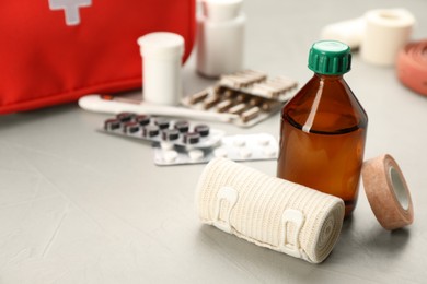Photo of Bandage, sticking plaster roll and medical alcohol on grey table, space for text. First aid kit