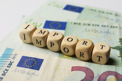 Word Import made of wooden cubes and banknotes on table, closeup