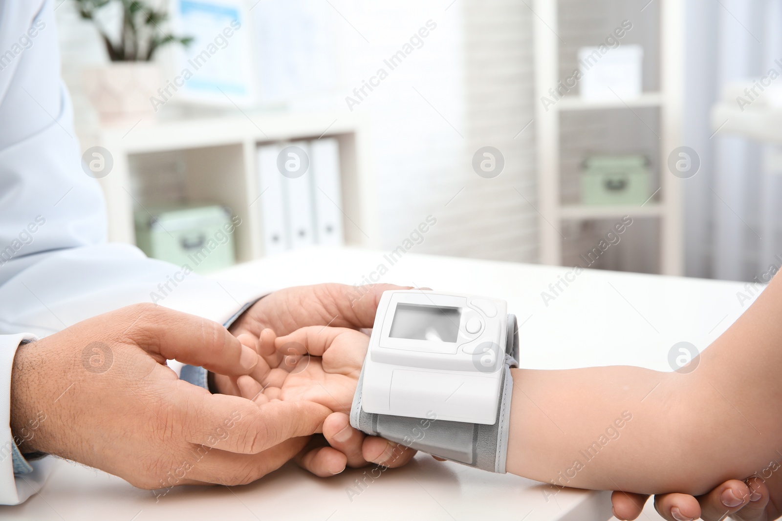 Photo of Doctor checking little girl's pulse with medical device in hospital, closeup