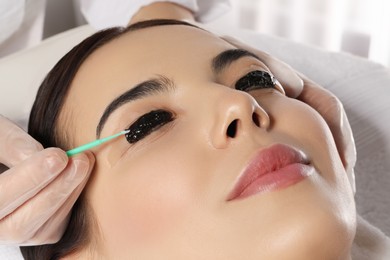 Photo of Young woman undergoing eyelash lamination and tint in salon, closeup