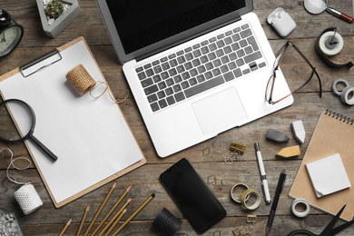 Photo of Flat lay composition with laptop, smartphone and stationery on wooden table. Designer's workplace