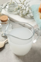 Photo of Glass jug with natural rice water on light grey table, closeup