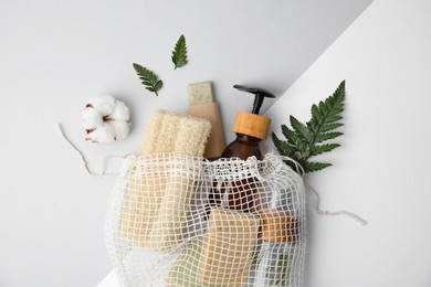 Photo of Mesh bag with eco friendly personal care products on color background, flat lay
