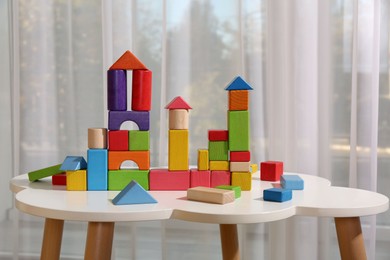 Photo of Colorful building blocks on white table in playroom