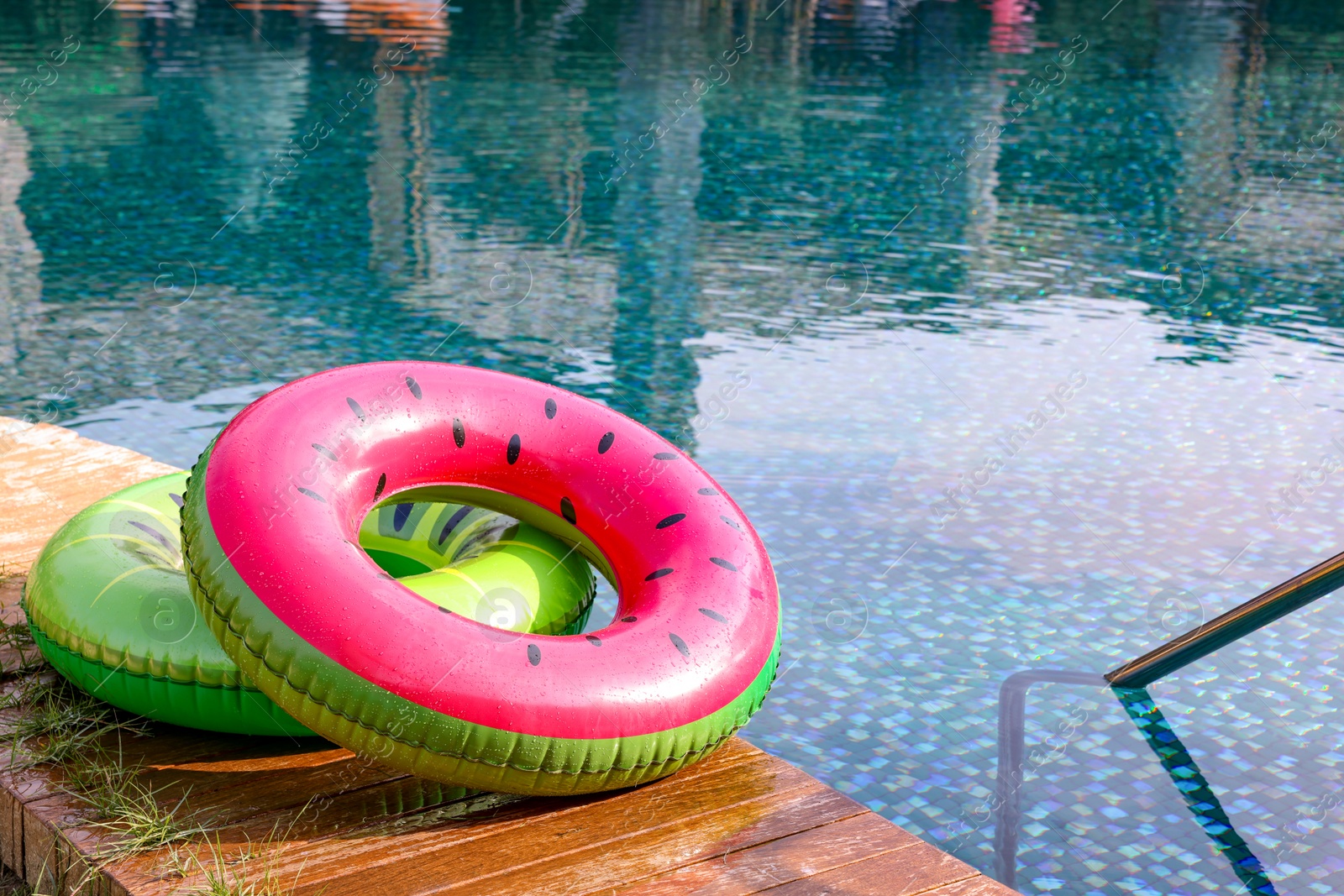 Photo of Inflatable rings on wooden deck near swimming pool. Luxury resort