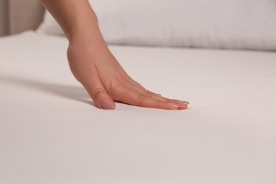 Photo of Woman touching soft white bedsheet, closeup view