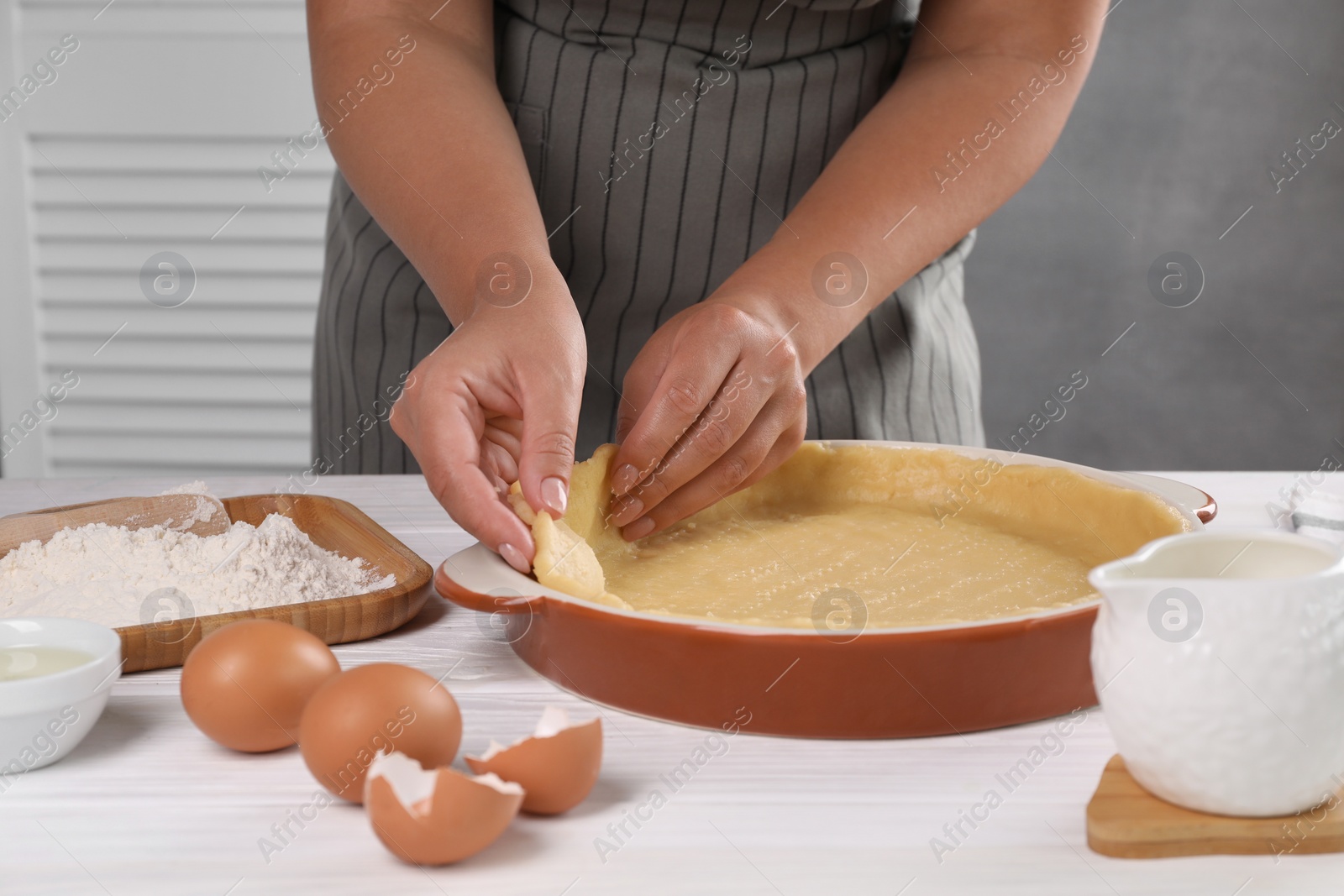 Photo of Woman making quiche at white wooden table, closeup