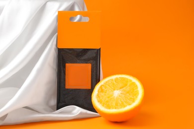 Photo of Scented sachet and half of orange on color background