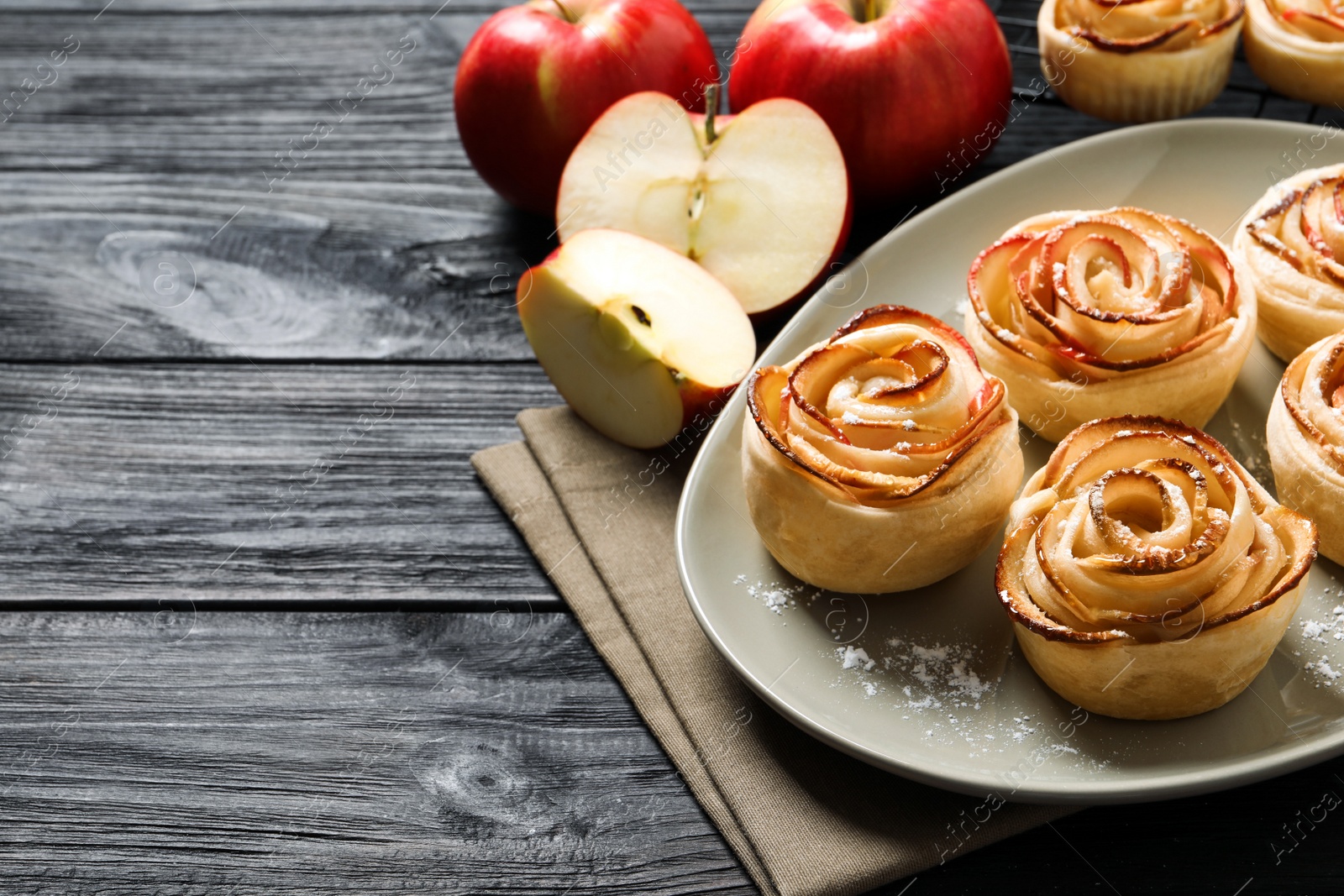 Photo of Freshly baked apple roses on dark wooden table, space for text. Beautiful dessert