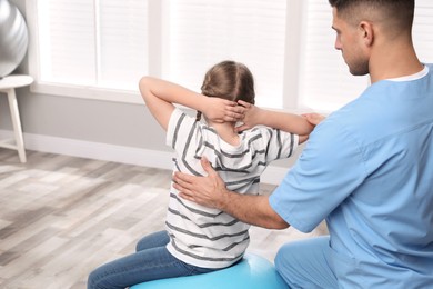 Photo of Orthopedist helping child to do exercise in clinic. Scoliosis treatment