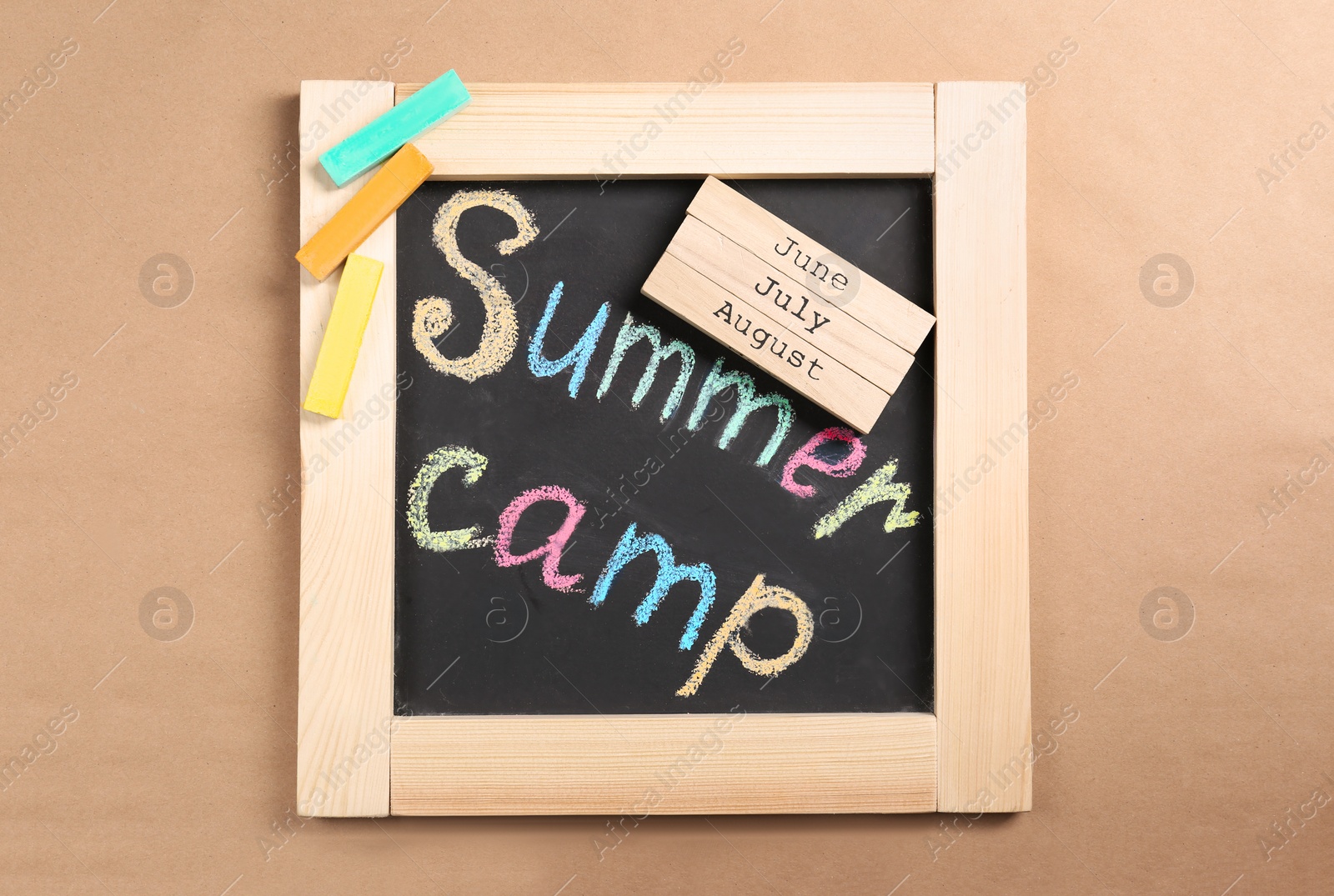 Photo of Composition with block calendar and words SUMMER CAMP written on small blackboard, top view