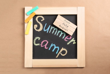 Photo of Composition with block calendar and words SUMMER CAMP written on small blackboard, top view