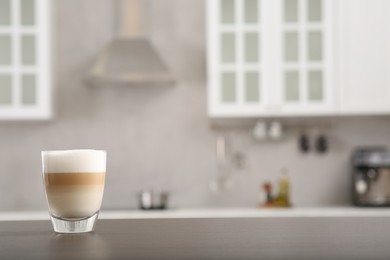 Glass of aromatic coffee on countertop in kitchen, space for text