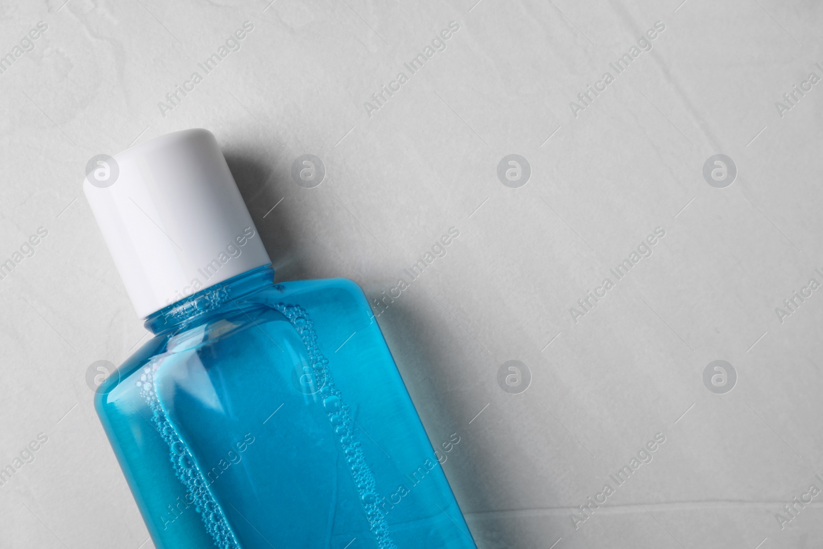 Photo of Fresh mouthwash in bottle on grey textured background, top view. Space for text