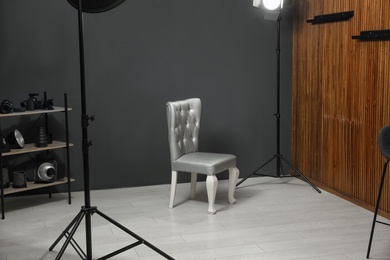 Photo of Stylish silver chair and professional equipment in photographer's studio