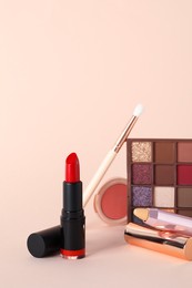 Photo of Beautiful red lipstick and cosmetic products on beige background
