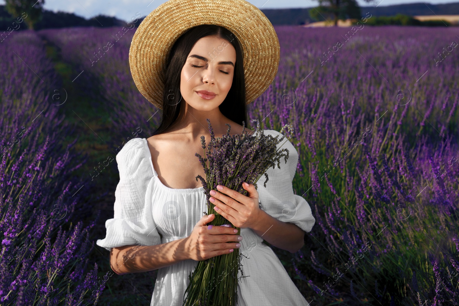 Photo of Beautiful young woman with bouquet in lavender field