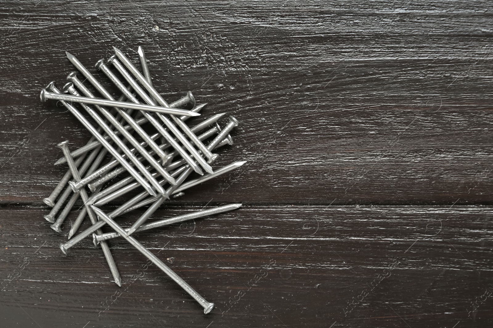 Photo of Many metal nails on wooden background, flat lay. Space for text