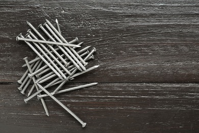 Photo of Many metal nails on wooden background, flat lay. Space for text