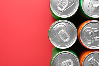 Energy drink in cans on red background, top view. Space for text