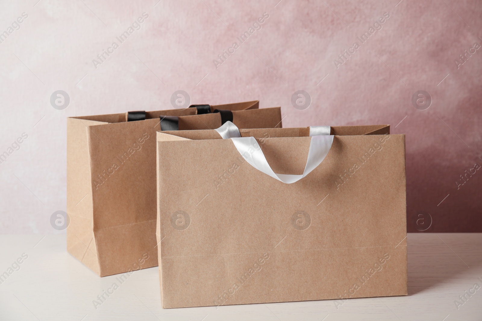 Photo of Paper shopping bags on table against color background. Mock up for design