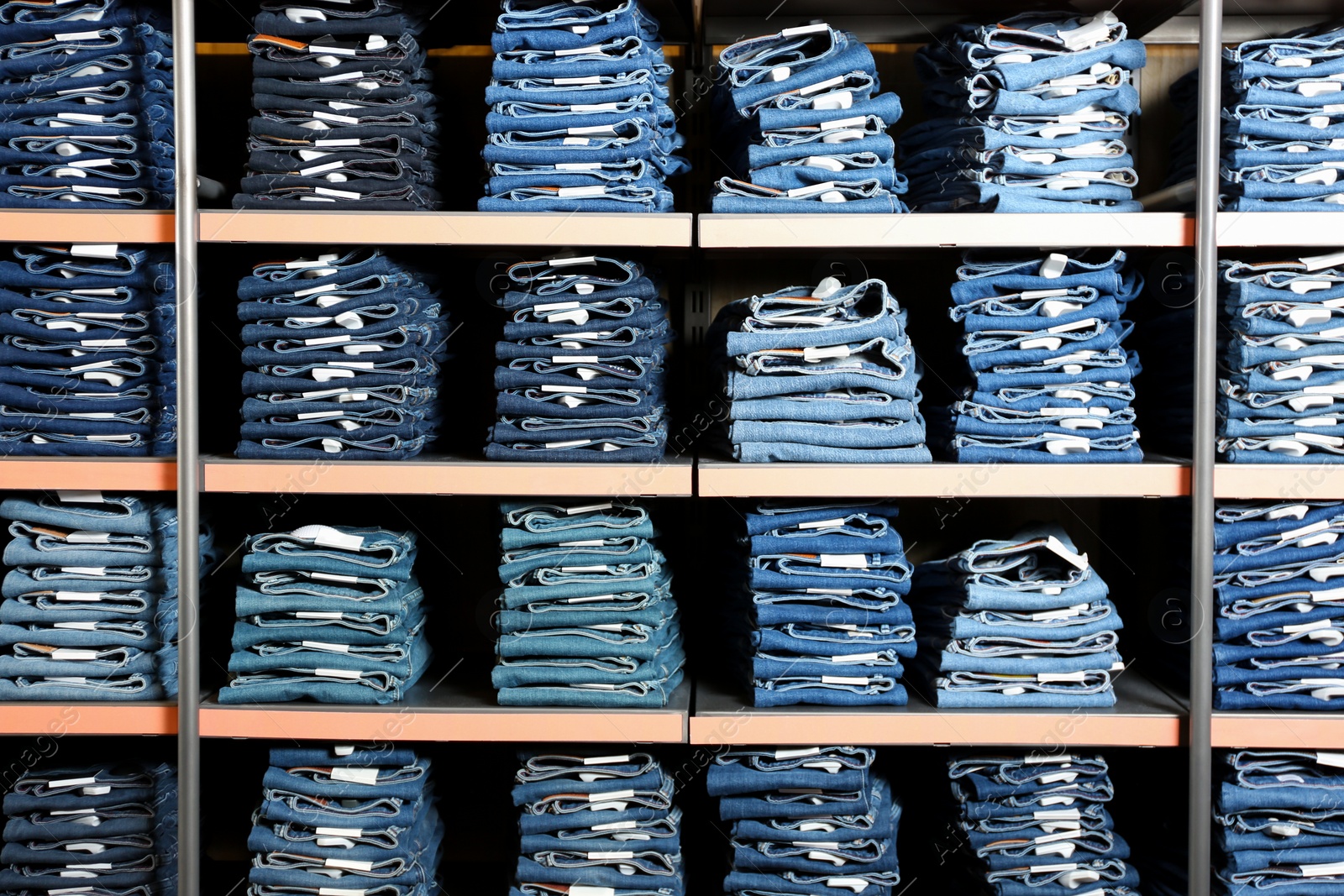 Photo of Collection of stylish jeans on shelves in shop