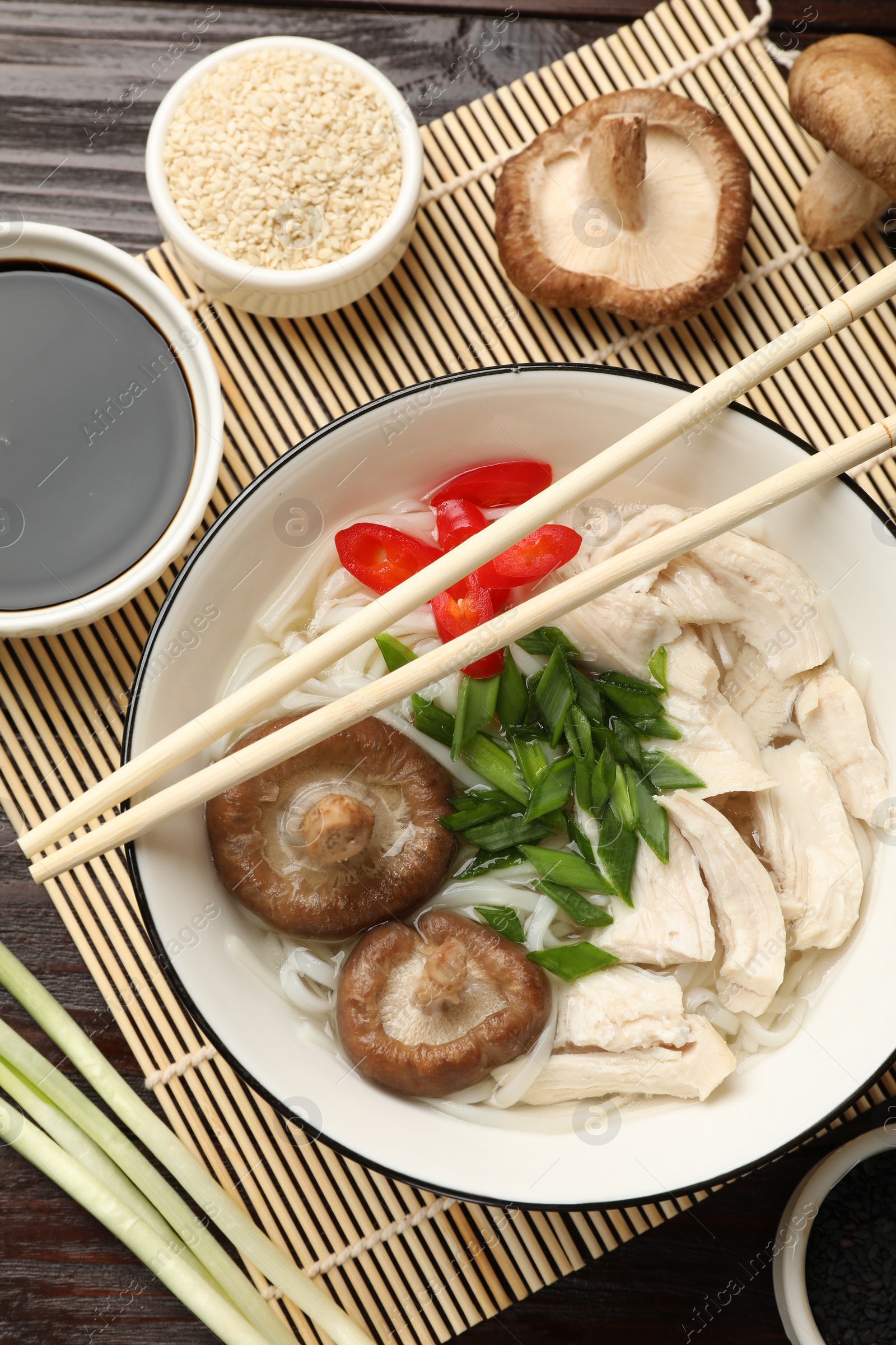 Photo of Delicious ramen with meat and ingredients on wooden table, flat lay. Noodle soup