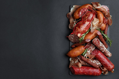 Photo of Different types of sausages served on black background, flat lay. Space for text